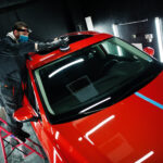 Car detailing concept. Man in face mask with orbital polisher in