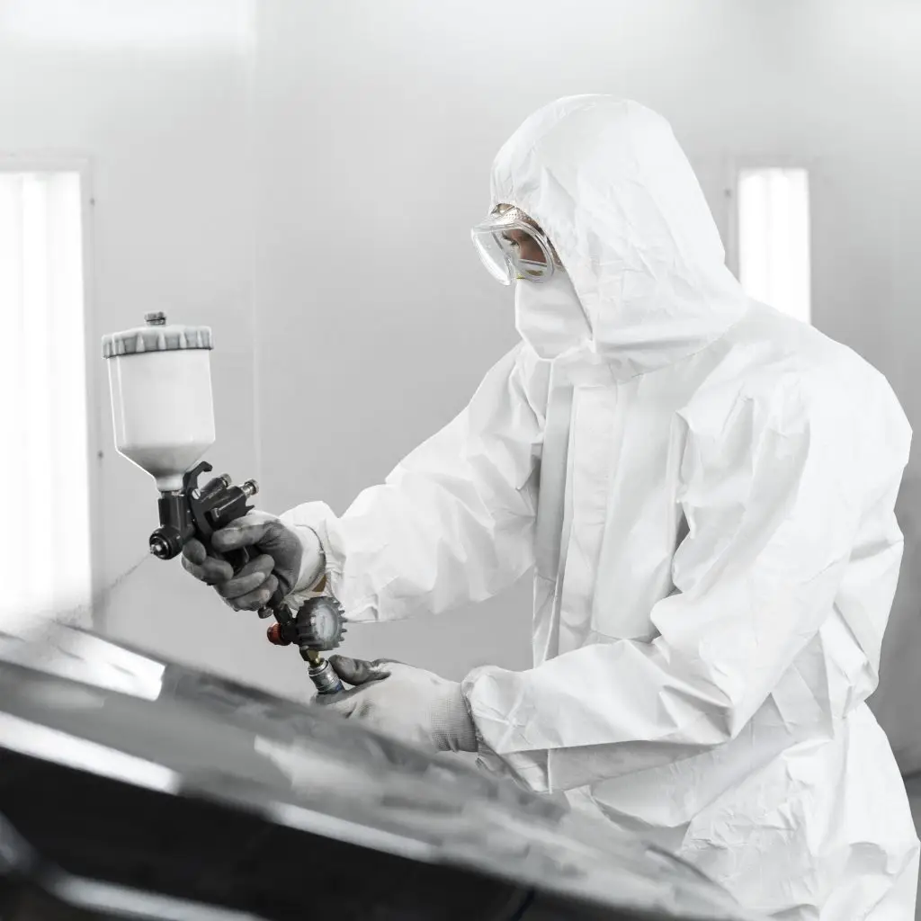 man hazmat suit using gun paint car shop