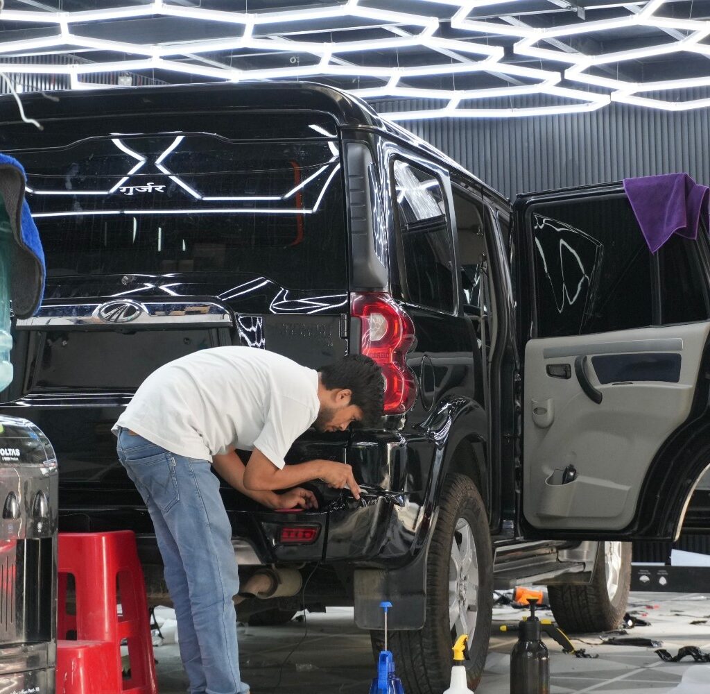 Master PPF installer performing seamless edge wrapping on a black Mahindra SUV in Noida